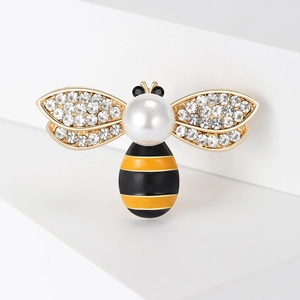 Elegante spilla a forma di ape dorata con cristalli e perla su supporto bianco minimalista