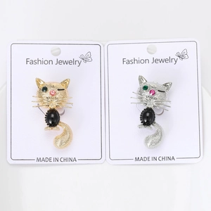 Détail de broches chat dorées et argentées avec pierres noires et yeux en strass brillants