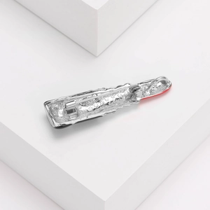 Détail de broche argentée avec émail rouge et fermoir de sécurité sur support blanc