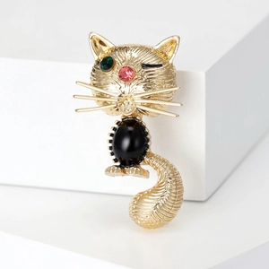 Détail de la broche chat dorée avec strass scintillants et une pierre noire ovale