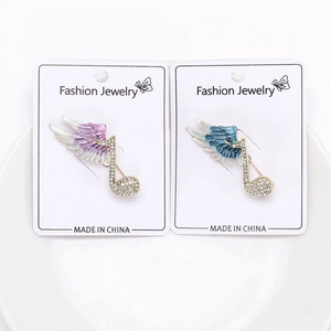 Macro detail of music note brooches with purple and blue wings on white card