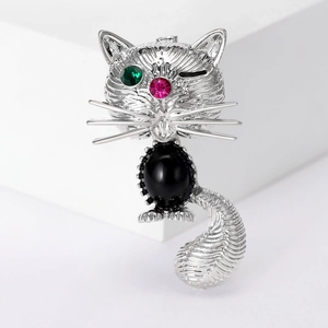 Détail d'une broche chat avec pierre noire et strass verts brillants sur les yeux