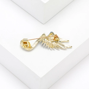 Detail view of musical note wing brooch back showing safety pin clasp and metal texture