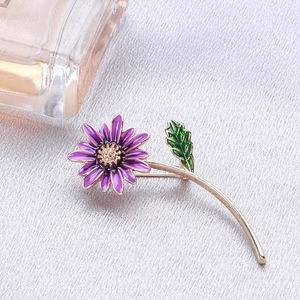 Détail de la broche marguerite violette avec pétales en émail et centre doré sur soie