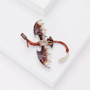 Détail d'une broche dragon en argent avec ailes en émail rouge et perles jaunes