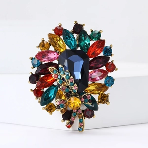 Macro shot of vintage gold alloy brooch with multicolor faceted crystals and central blue gem