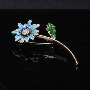 Vue détaillée de la broche fleur en émail bleu avec pétales dorés sur fond noir brillant