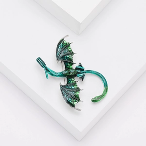 Détail macro d'une broche dragon en émail vert avec écailles sur pierre blanche