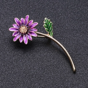 Gros plan sur la broche marguerite violette en émail et tiges dorées sur cuir noir
