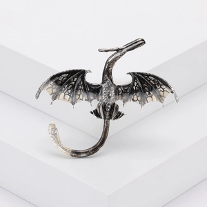 Gros plan d'une broche dragon vintage avec ailes argentées et écailles de dragon texturées