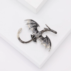 Vue détaillée d'une broche dragon argentée avec des textures d'ailes en émail