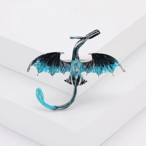 Détail d'une broche dragon avec émail bleu et cristaux brillants sur fond blanc
