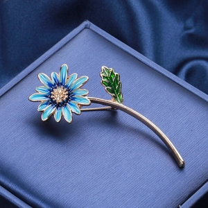 Détail de la broche marguerite en émail bleu avec placage à l'or et cœur en cristal brillant