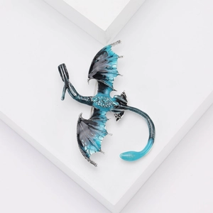 Vue détaillée de la broche dragon avec émail bleu et petits strass bleus incrustés sur l'aile