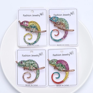 Macro view of four colorful chameleon brooches with crystals on white jewelry cards
