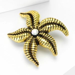Macro shot of vintage gold starfish lapel pin with textured details and crystal center
