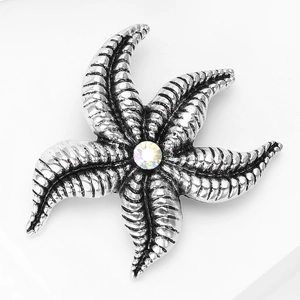 Close-up of starfish brooch with antique silver texture and a sparkling central rhinestone