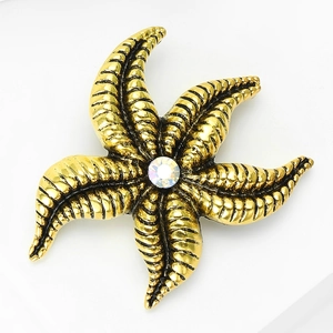 Macro shot of gold starfish brooch featuring granular texture and a center crystal