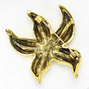 Detail view of the back of a gold-plated starfish brooch with a metal pin fastening