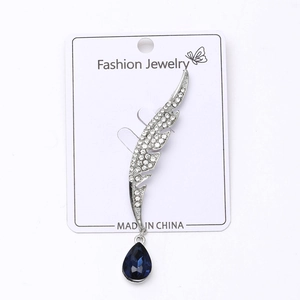 Détail de la broche plume argentée avec strass blancs et pendentif goutte bleue
