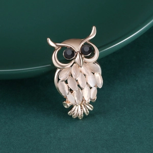 Détail d'une broche hibou avec des pierres œil-de-chat blanches et des yeux en gemmes noires