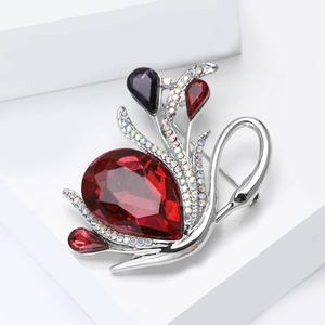 Macro view of crystal swan brooch with red pear-shaped gemstone and white diamonds