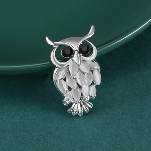 Détail de la broche hibou avec pierres marquise blanches et yeux noirs sur céramique verte