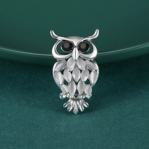 Détail d'une broche hibou avec cadre en alliage d'argent et pierres œil de chat