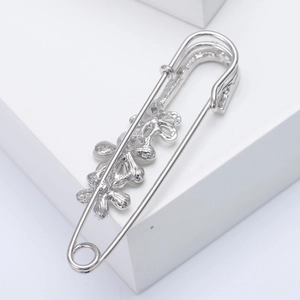 Close-up of polished silver flower brooch pin on a minimalist white display stand