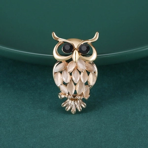 Détail de la broche hibou avec tête en alliage doré et plumes en pierre œil de chat