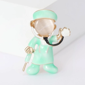 Cartoon doctor brooch with green enamel, stethoscope detail and opal stone inlay