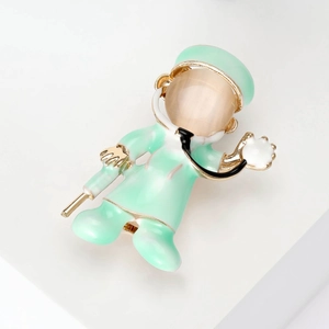 Macro detail of cartoon doctor brooch with mint green enamel and pink cat eye stone