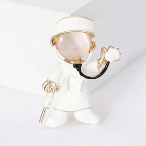 Detail of cartoon doctor brooch with opal face, golden base and enamel tools