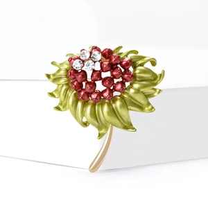 Dettaglio spilla fiore di melograno smaltato con bacche rosse e strass scintillanti