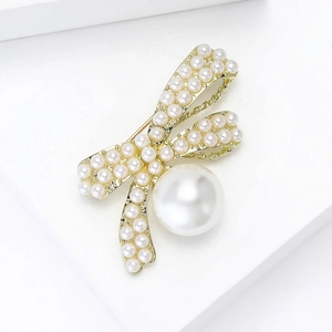 Detail of elegant gold bow brooch with white pearls on a minimalist white background