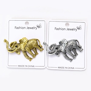 Close-up of elephant brooches with antique textures in gold and silver finish on display card