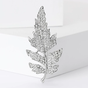 Détail d'une broche en forme de feuille argentée avec strass brillants sur marches