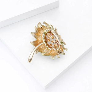 Dettaglio del retro della spilla a girasole dorata con chiusura su supporto bianco