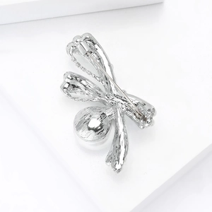 Detailed macro view showing the silver bow brooch back with rotating safety lock mechanism