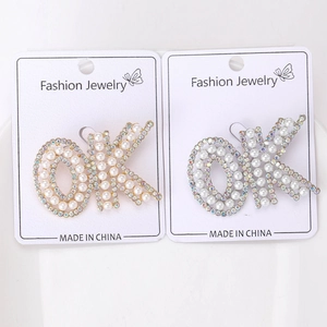 Détail de broches lettre OK avec perles blanches et strass brillants en dorée et argentée