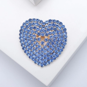 Elegant heart-shaped brooch with blue rhinestones and hollow design on a white pedestal