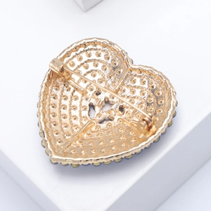 Detail view showing back of gold heart brooch with safety pin and textured metal finish