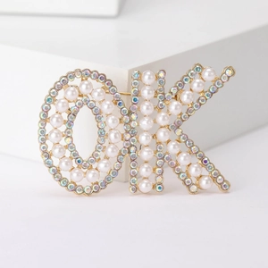 Détail de la broche OK ornée de perles blanches et de strass colorés étincelants