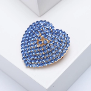 Golden heart brooch with blue rhinestones pave-set on a geometric stone background
