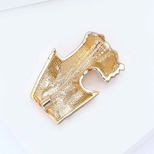 Macro detail of golden alloy brooch back featuring matte finish and safety pin clasp