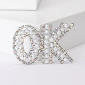 Détail de la broche lettre OK avec perles blanches et strass AB scintillants