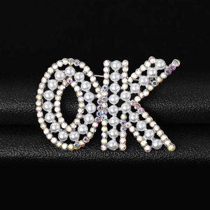 Vue macro d'une broche en forme de lettre OK avec perles et strass multicolores