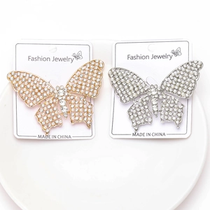 Détail de broches papillon avec strass brillants et perles sur un plateau blanc élégant