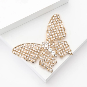 Broche papillon dorée avec perles et cristaux sur support géométrique blanc