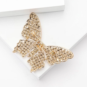 Détail d'une broche papillon dorée avec des ailes en filigrane et une épingle au dos